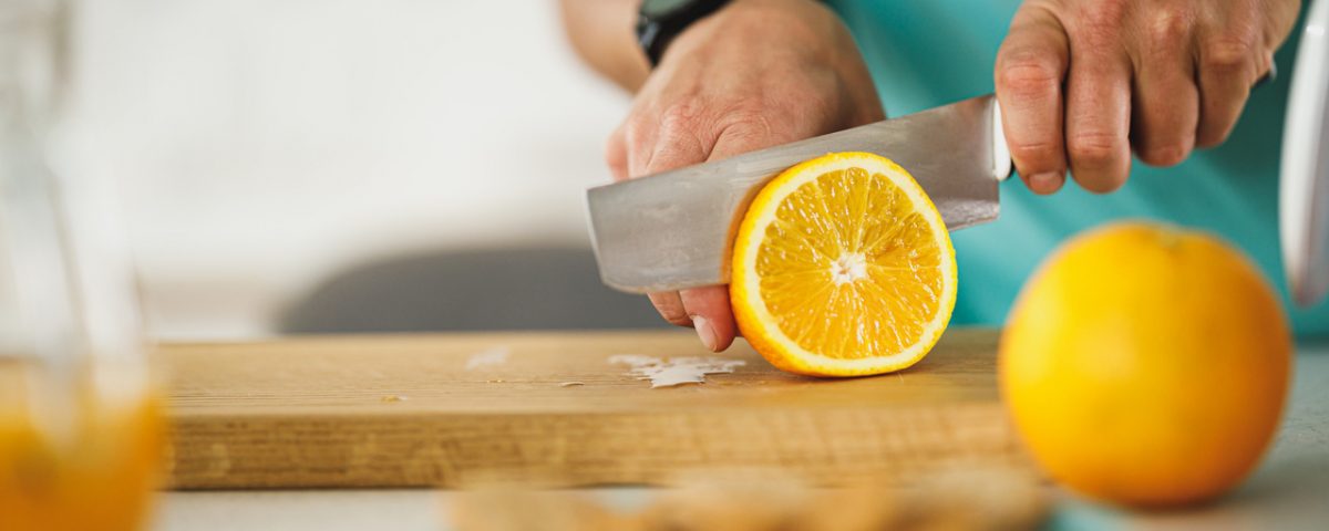 pessoa cortando uma laranja para saber como evitar pedra nos rins