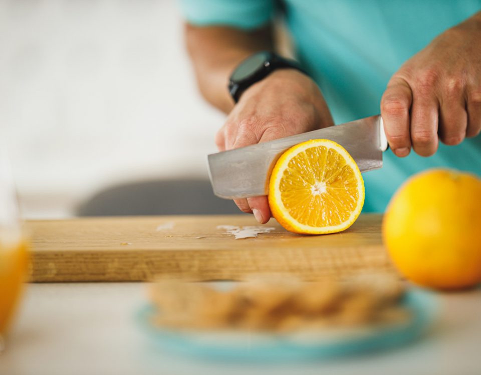 pessoa cortando uma laranja para saber como evitar pedra nos rins