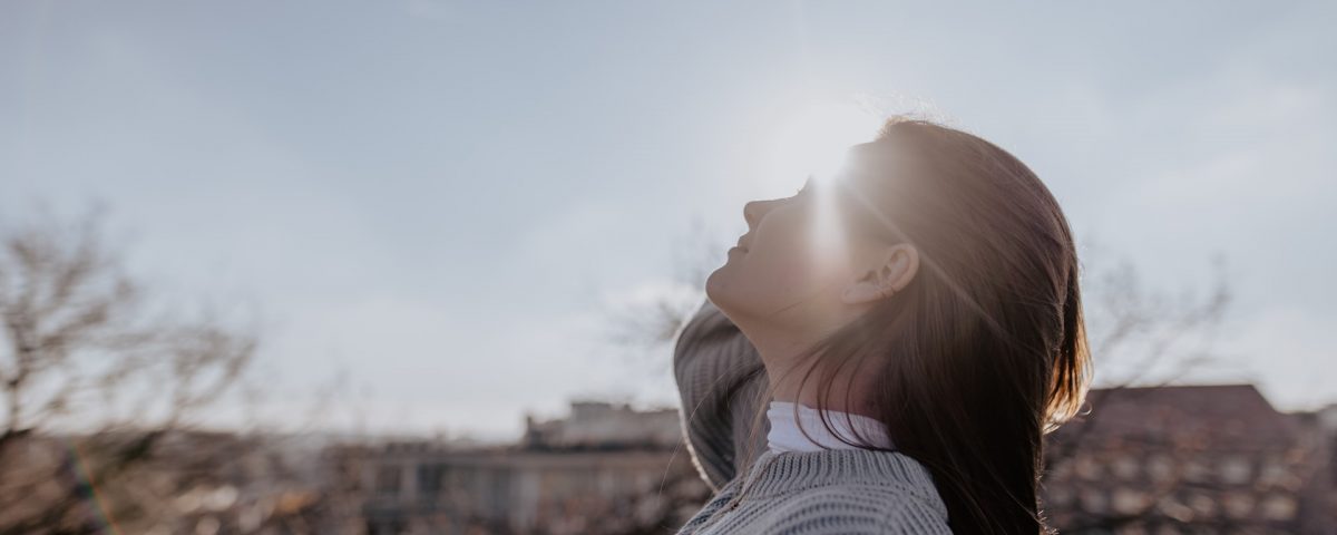 mulher em frente ao sol para contextualizar a falta de vitamina d