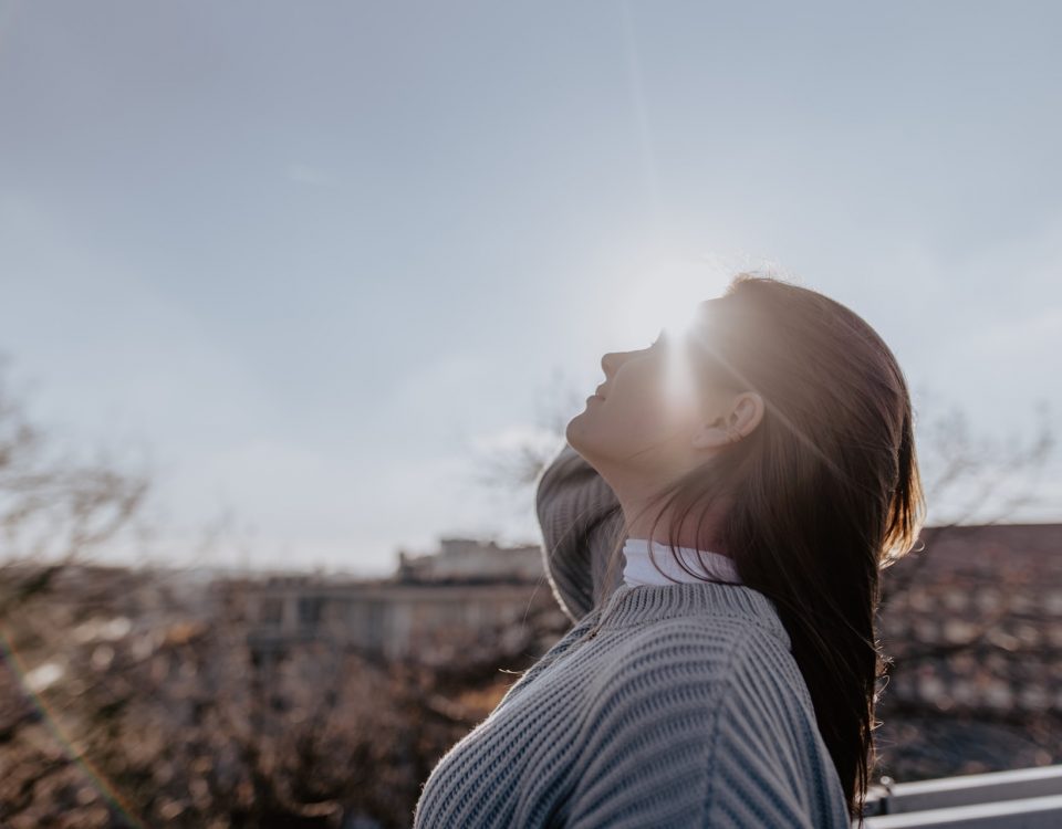 mulher em frente ao sol para contextualizar a falta de vitamina d